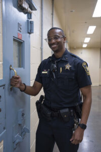 Deputy in blue uniform checking the handle of a cell door